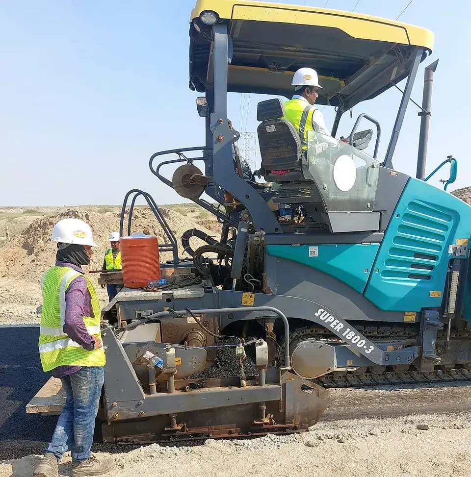 Paver operator and crew on the road works