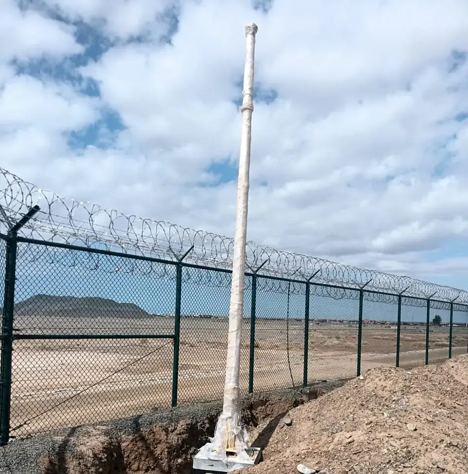 Chain-link perimeter fence with concertina wire and lighting pole
