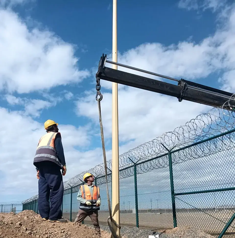 Crane lifting a perimeter lighting pole into position